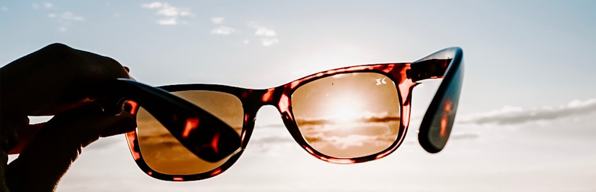 Sunglasses Lens Technology Banner. Sunglasses held up to the sun.